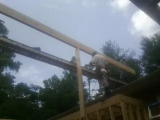 Carpenter setting a ridge beam over a new addition frame — Ice Dam Removal by Roofing Brothers in La Pine