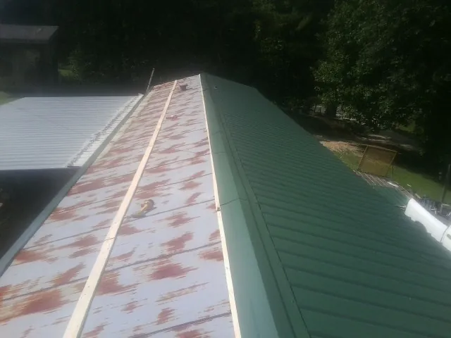 Old rusted panels beside newly installed green metal roofing — Wind Damage Roof Repair by Roofing Brothers in La Pine