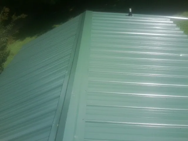 New green metal panels meeting at the ridge of a roof — Flat Roof Repair work by our crew in La Pine