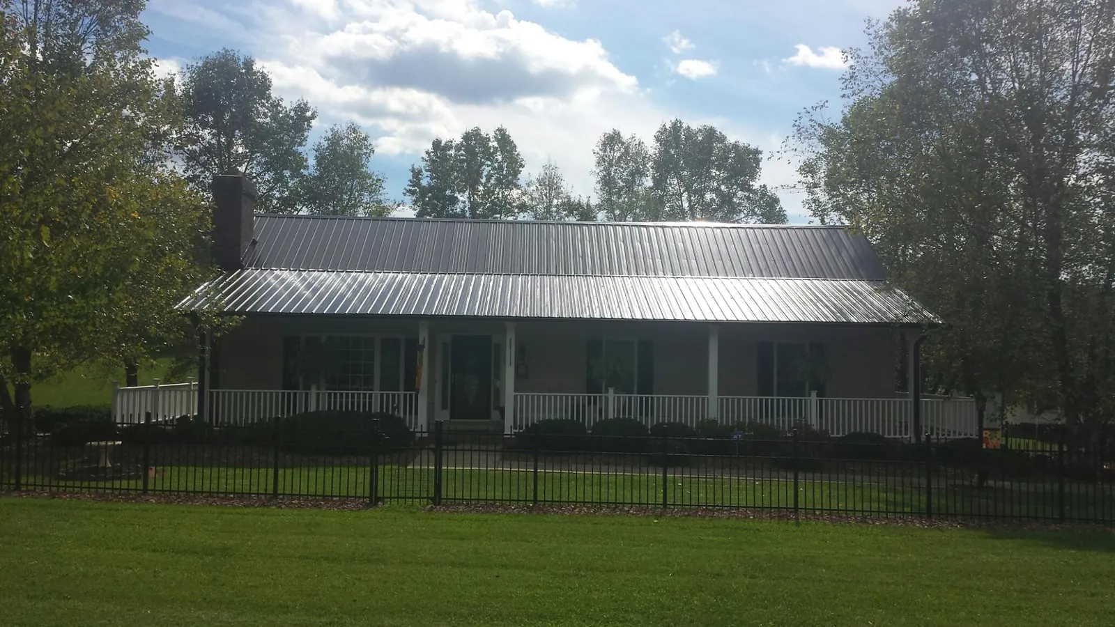 Gray metal roof on a brick ranch with a full width front porch — Gutter Guard Installation work by our crew in La Pine
