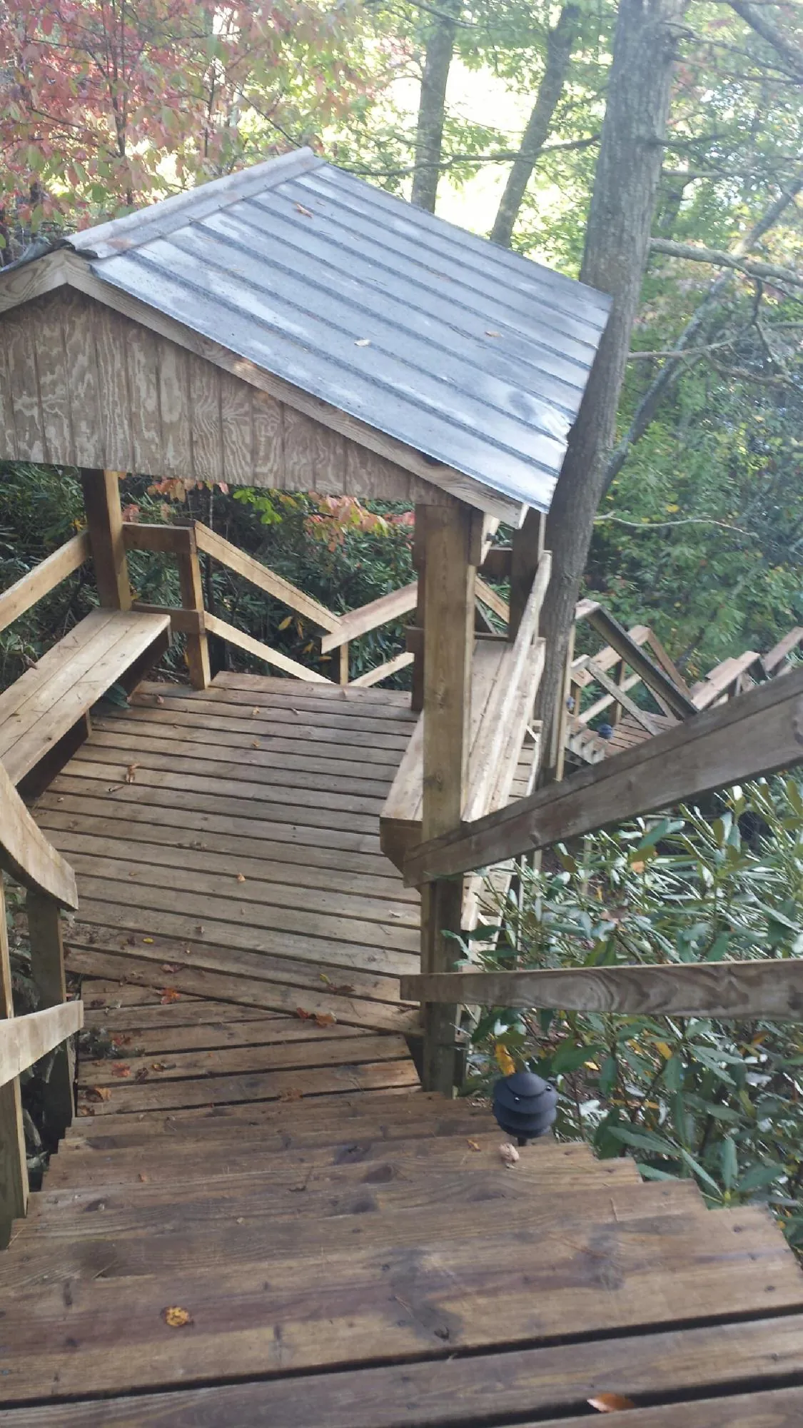 Metal roofed shelter over wooden steps on a wooded walkway — Skylight Repair & Installation work by our crew in La Pine