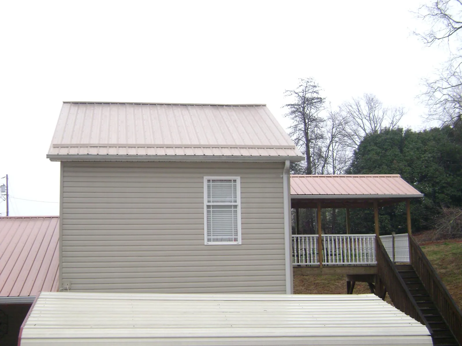 Tan metal roofs on a two story addition and attached porch, from a Roof Replacement job in La Pine